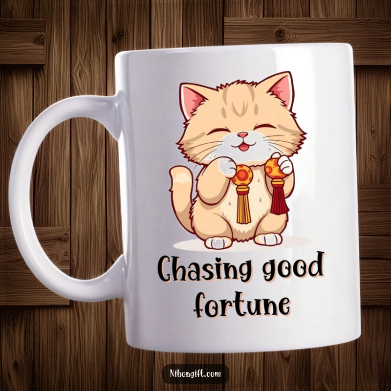 Funny cat mug showing a fluffy cat in a playful crouch batting at a dangling lucky charm with intense focus.