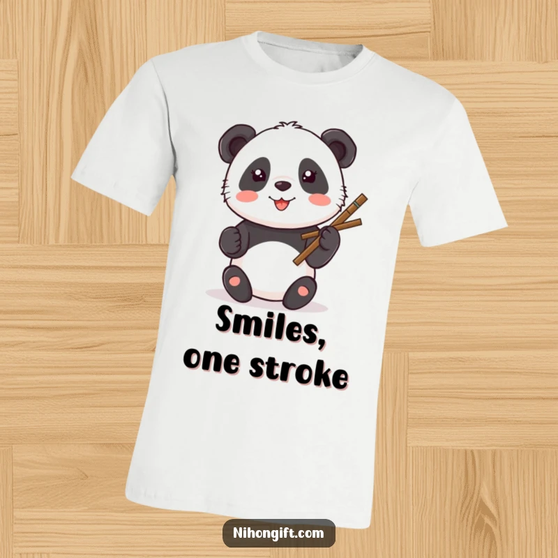 Funny Kawaii Panda T-Shirt showing a panda painting a smiley face with a calligraphy brush.
