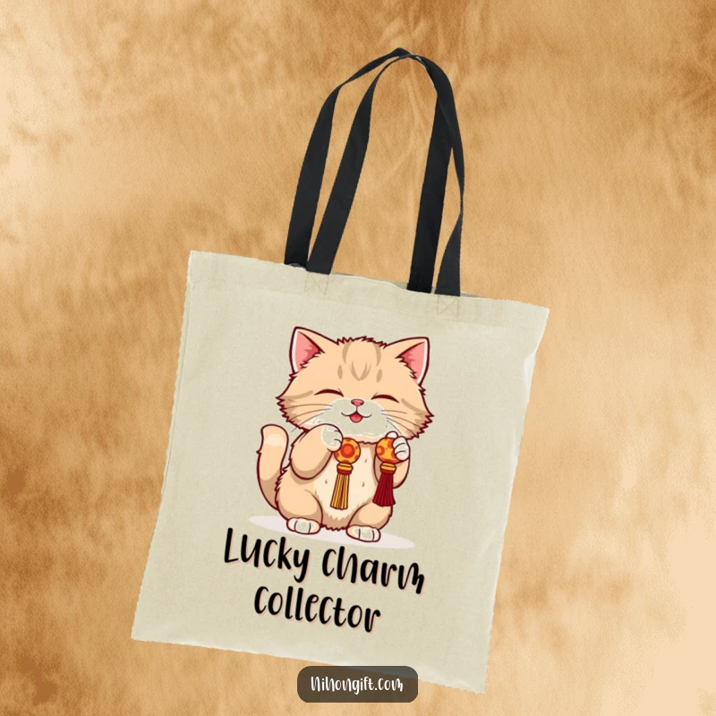 Funny cat tote bag with a fluffy cat in a playful crouch batting at a dangling lucky charm.
