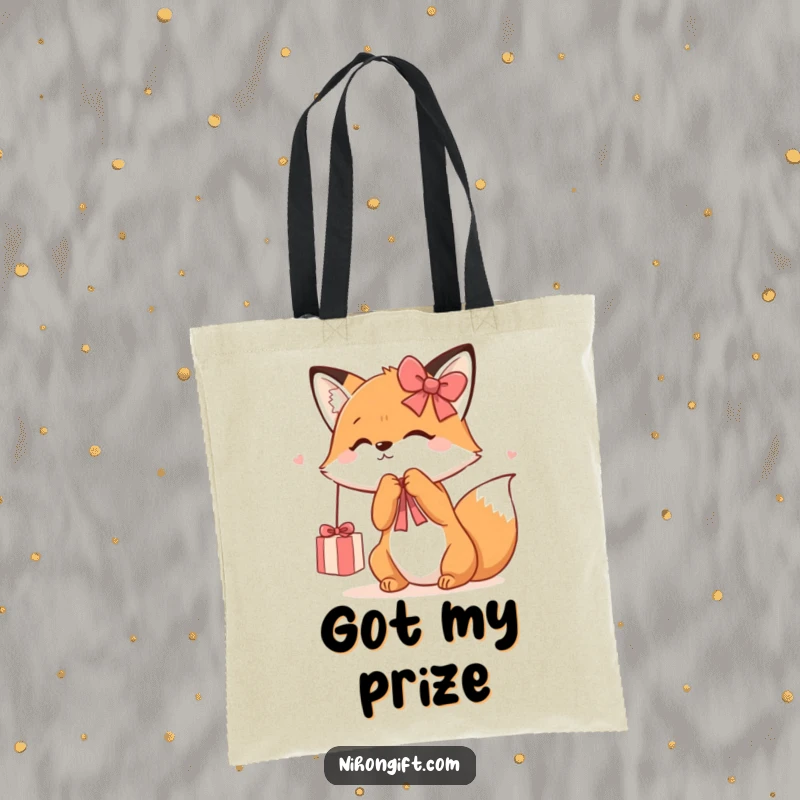 Funny Kawaii Fox Tote Bag depicting a cute fox playfully batting at a dangling gift ribbon, perfect for carrying essentials with style.